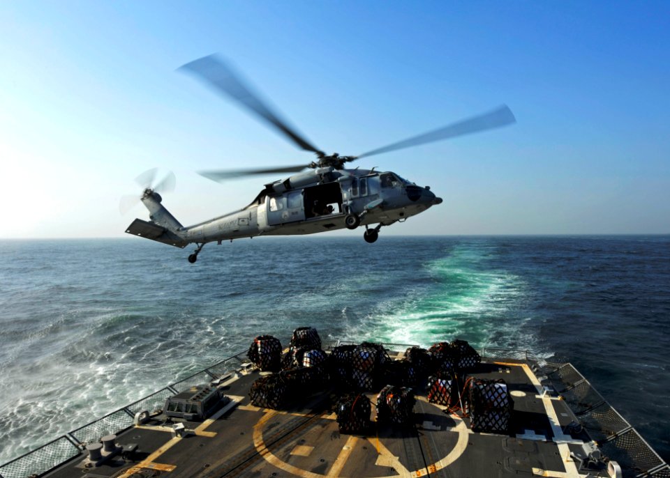 US Navy 111213-N-VH839-027 A helicopter turns away from the flight deck after lowering pallets of food