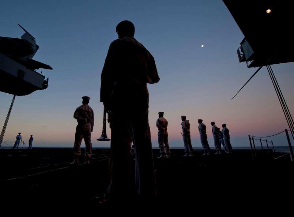 US Navy 111213-N-DR144-035 Sailors assigned to a burial detail wait to begin a burial at sea ceremony for 22 former service members at dawn aboard