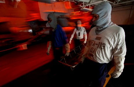 US Navy 111219-N-DR144-084 Stretcher bearers move in to evacuate casualties during a general quarters drill in the hangar bay aboard the Nimitz-cla