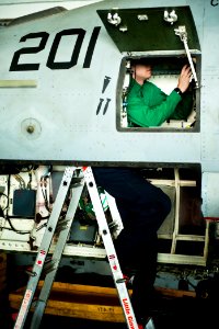 US Navy 111215-N-BT887-216 Aviation Electronics Technician 3rd Class Brenton Campbell performs maintenance on an F-A-18E Super Hornet aboard the Ni