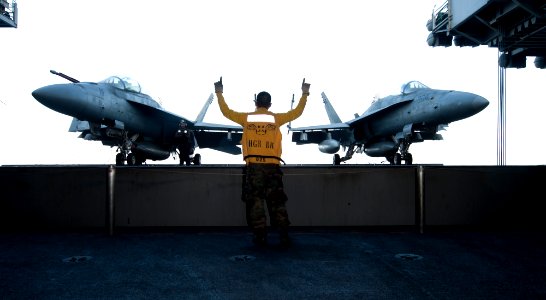 US Navy 111219-N-OY799-174 Aviation Boatswain's Mate (Handling) Airman Rae Michael Valencia, from Dedeo, Guam, signals for the raising of aircraft