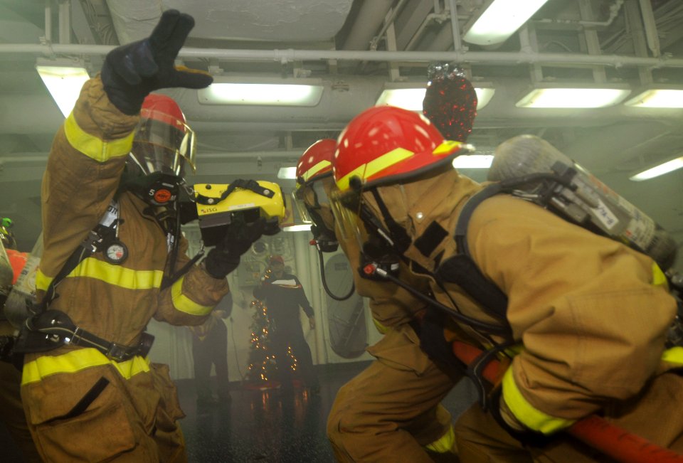 US Navy 111215-N-KA046-178 A Sailor signals to the hose team to get low for safety