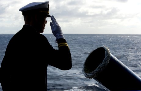 US Navy 111215-N-VO377-017 Lt. David L. Duprey salutes after committing the cremated remains of a former Sailor to the deep during a burial at sea photo
