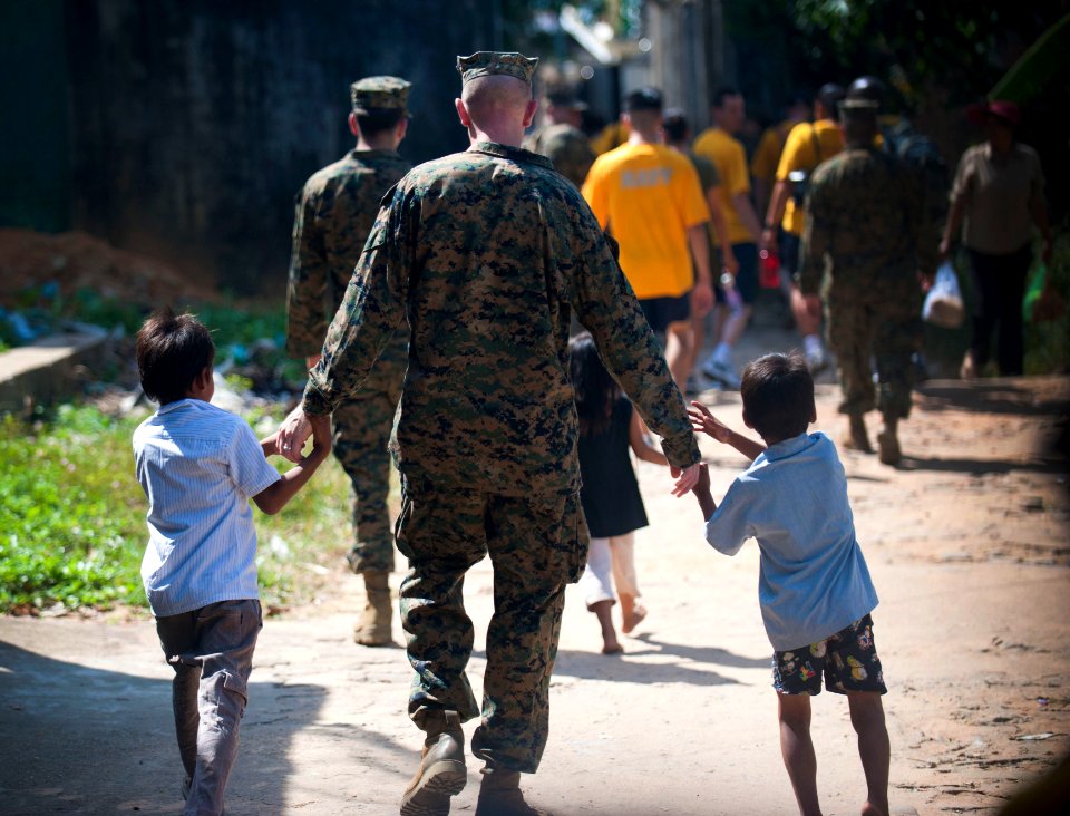 US Navy 111215-N-PB383-615 A Marine assigned to the 11th Marine Expeditionary Unit (11th MEU) walks with children during a community service event