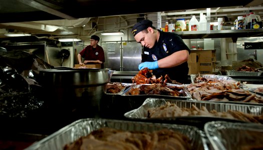 US Navy 111220-N-OY799-148 Culinary Specialist 3rd Class David Yuzon carves slices of turkey in preparation for the Christmas meal in the aft galle