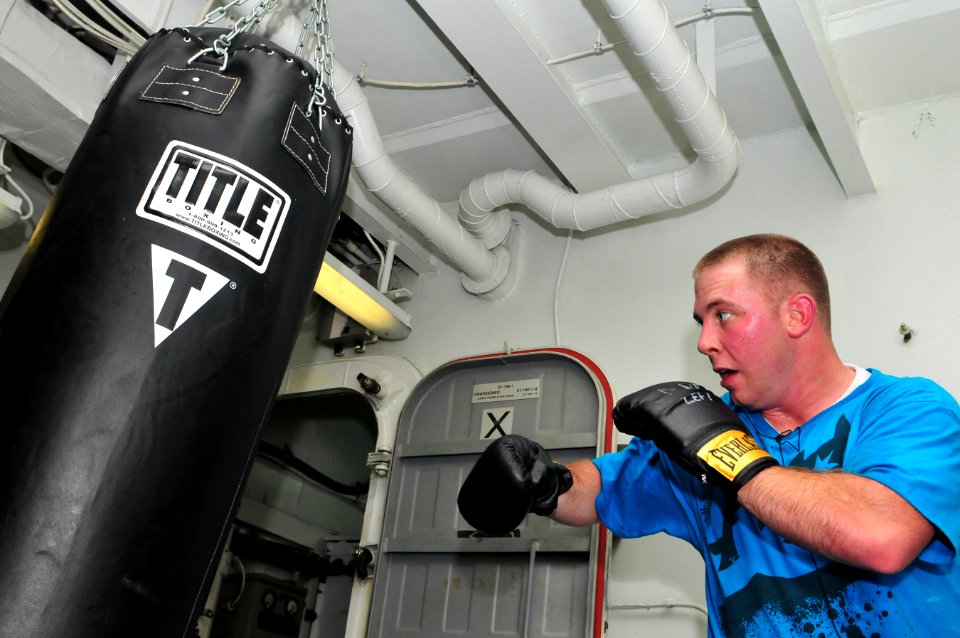 US Navy 111217-N-ZI635-061 Aviation Boatswain's Mate (Handling) 2nd Class Joshua Mee makes use of the heavy bags in the gym aboard the Nimitz-class