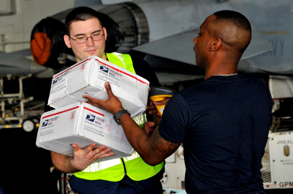 US Navy 111220-N-ZI635-459 Logistics Specialist Seaman Justin McLaurin, right, scans packages as mail arrives aboard the Nimitz-class aircraft carr