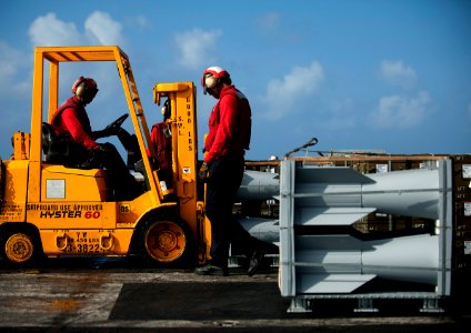 US Navy 111222-N-DR144-084 Aviation Ordnancemen assigned to Weapons Department's G-1 Division position crates of ordnance aboard the Nimitz-class a