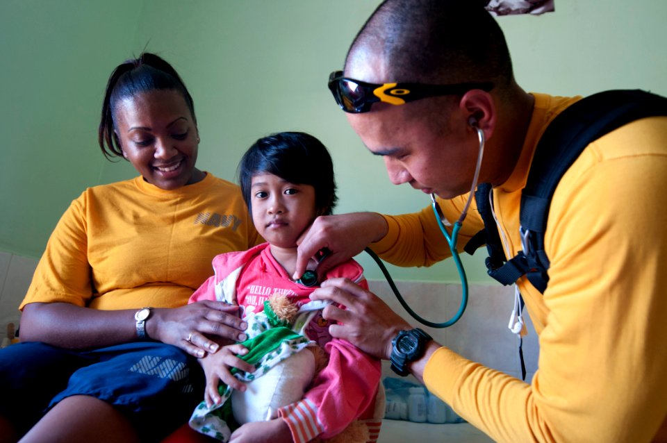US Navy 111219-N-PB383-179 Culinary Specialist 2nd Class Latoya Farrish, left, comforts a child as Hospital Corpsman 1st Class Joseph Samonte check