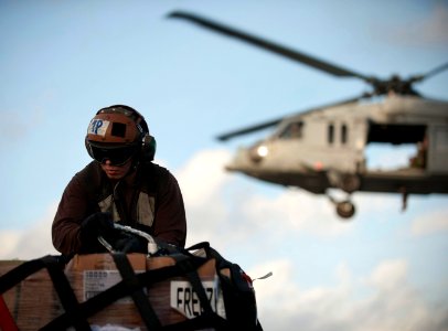 US Navy 111220-N-DR144-405 A Sailor removes cargo netting from a pallet of stores as an MH-60S Sea Hawk helicopter delivers supplies