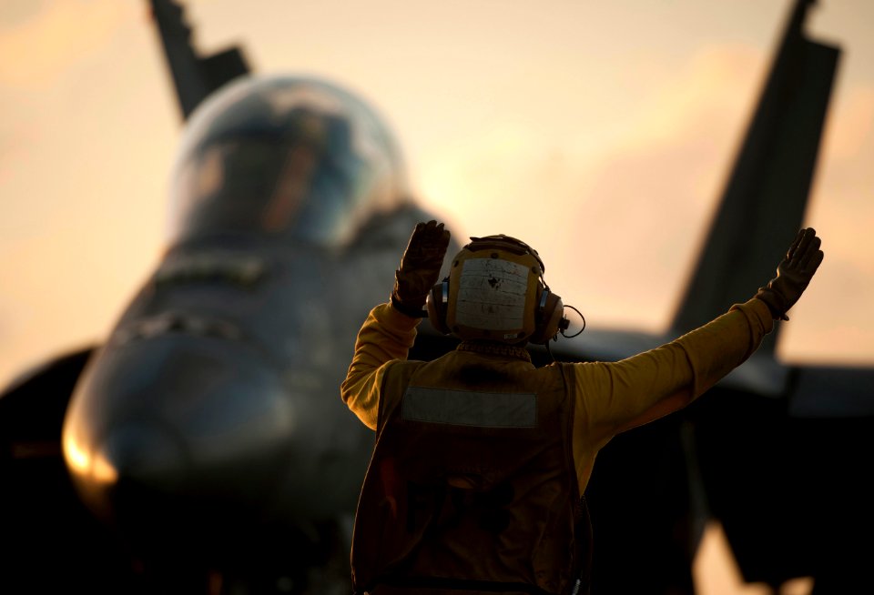 US Navy 111221-N-DR144-241 An aircraft director guides an F-A-18F Super Hornet to the waist catapults for launch on the flight deck aboard the Nimi