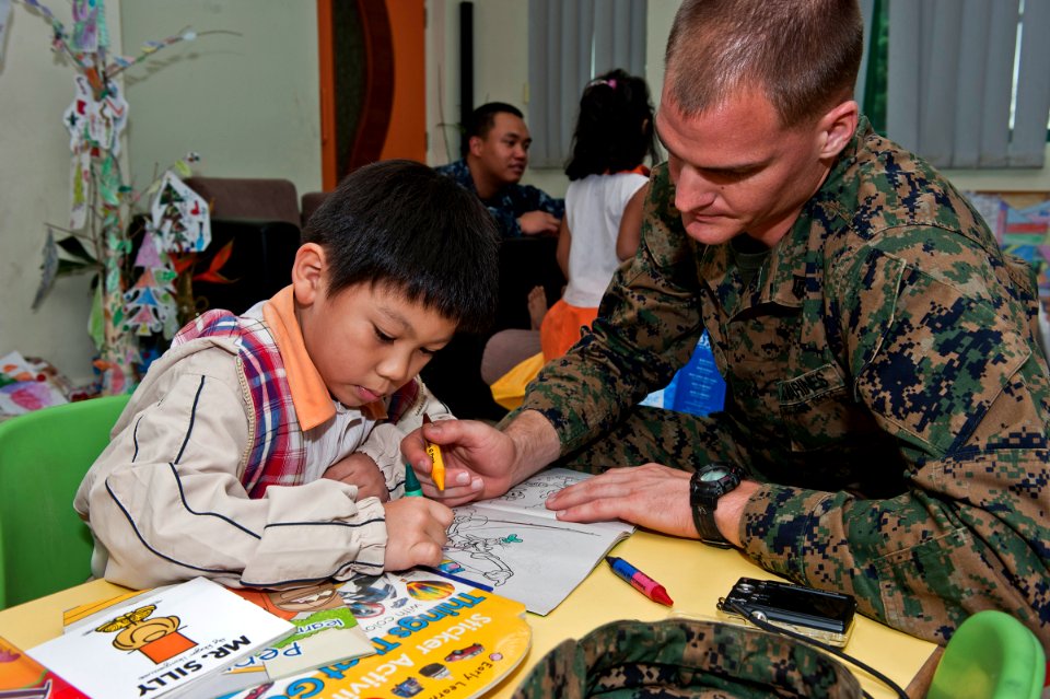 US Navy 111222-N-DX615-107 Sgt. Benjamin Wooden, assigned to the 11th Marine Expeditionary Unit (11th MEU), colors with a boy at Singapore's Child