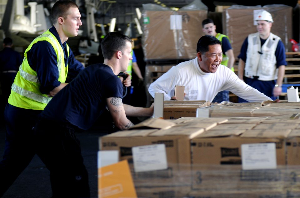 US Navy 111221-N-RG587-127 Chief Warrant Officer Loreto A. Lagrisola helps Sailors organize pallets of food in the hangar bay during a replenishmen