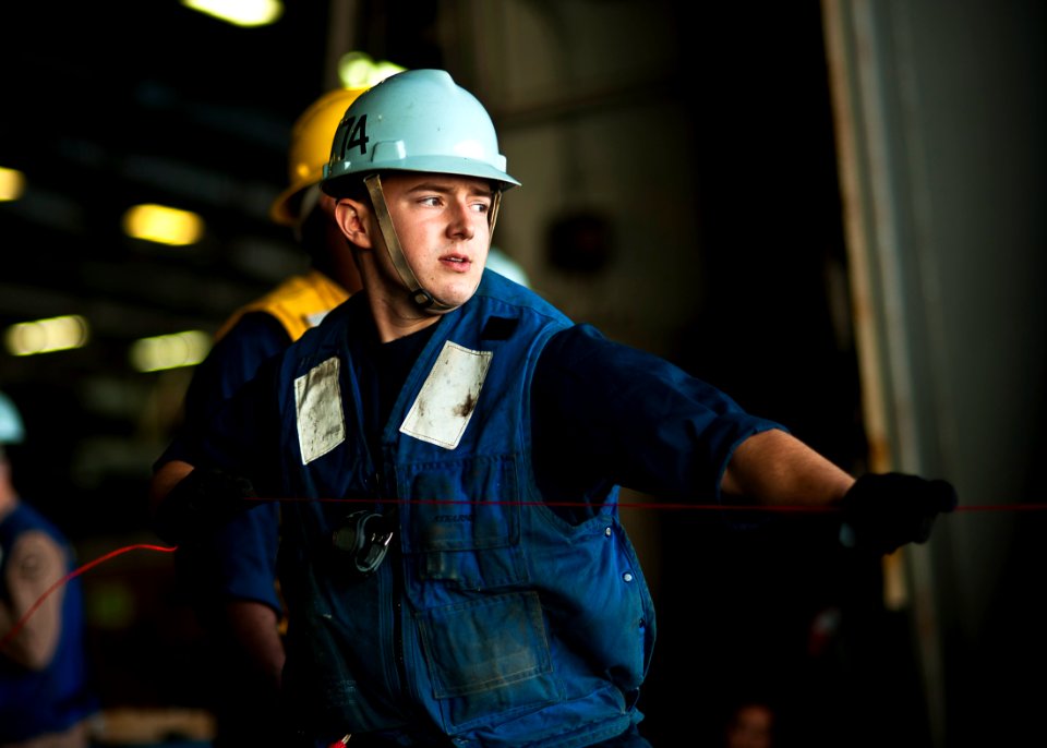US Navy 111221-N-BT887-054 Seaman Jesse Witt pulls in a line from the Military Sealift Command fast combat support ship USNS Rainier (T-AOE 7)