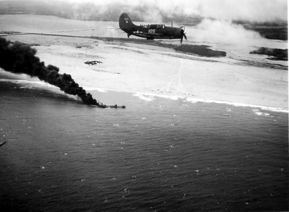 US Navy Helldiver flying over a burning Japanese tanker January 1945