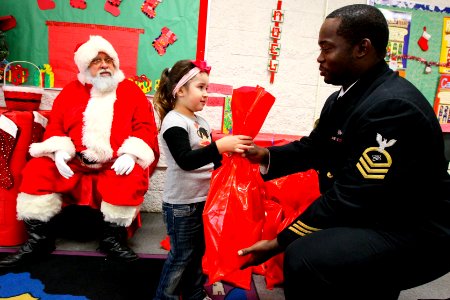 US Navy 111219-N-HW977-225 Chief Petty Officer Andra Hall, right, assigned to Naval Surface Warfare Center (NSWC) Corona, gives a gift to a child d photo