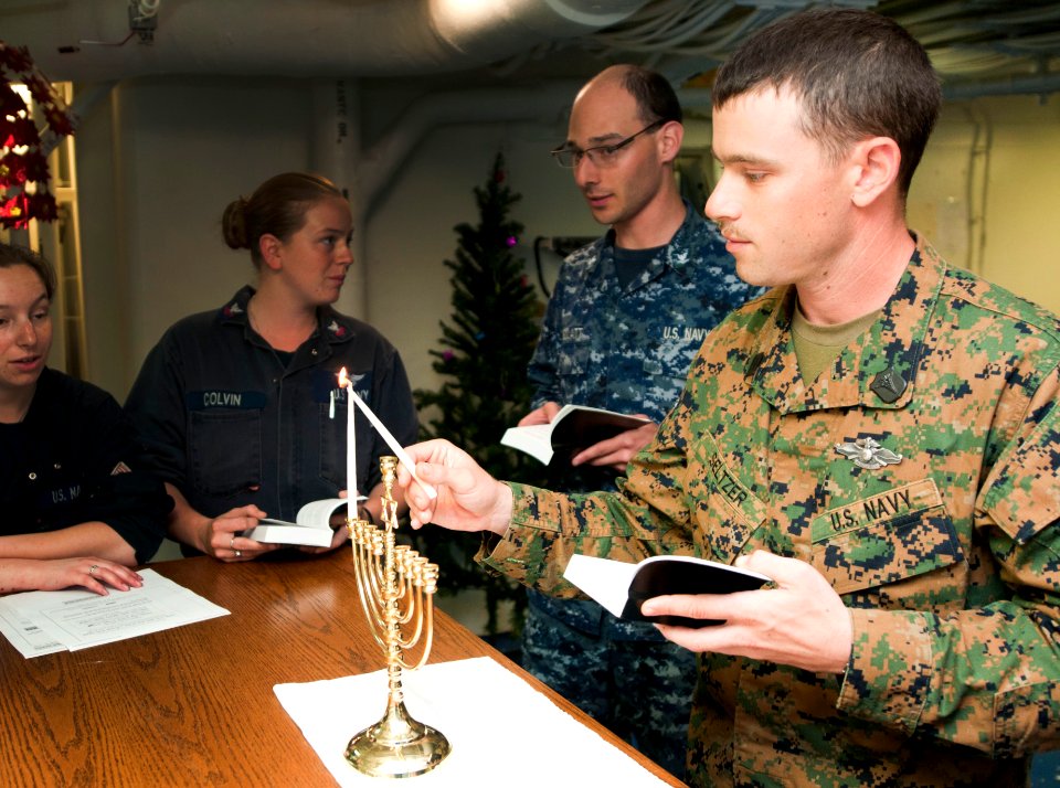 US Navy 111220-N-PB383-542 Hospitalman Aaron Seltzer, assigned to the 11th Marine Expeditionary Unit (11th MEU), lights a Menorah in observance of