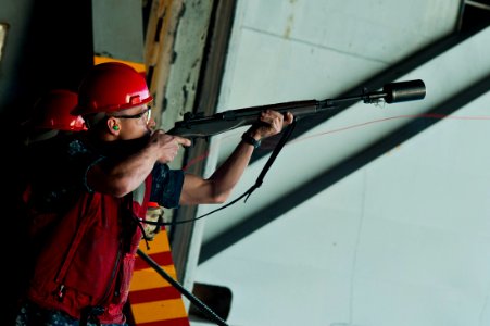 US Navy 111221-N-BT887-031 Gunner's Mate 3rd Class Chance Adams fires a line to the Military Sealift Command fast combat support ship USNS Rainier