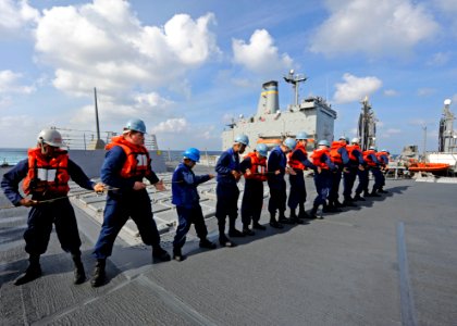 US Navy 111221-N-VH839-003 Sailors aboard the Arleigh Burke-class guided-missile destroyer USS Dewey (DDG 105) heave a line connected to a fueling