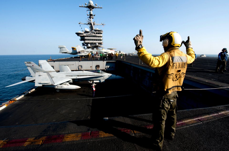 US Navy 111229-N-OY799-238 Aviation Boatswain's Mate (Handling) 2nd Class Roberto Andiarena signals for the raising of aircraft elevator one on the