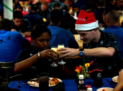 US Navy 111225-N-DR144-033 Machinist's Mate 3rd Class Nazierah Dowell and Electronics Technician 3rd Class Bryan McGee toast over Christmas dinner