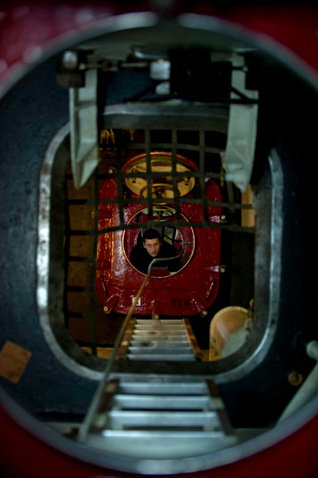 US Navy 111223-N-DR144-203 Interior Communications Electrician Fireman Michael Liermann ascends an access trunk after completing maintenance on the
