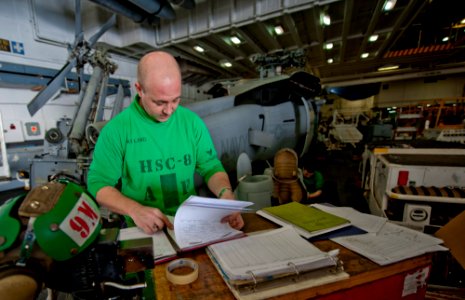 US Navy 111231-N-OY799-223 Aviation Structural Mechanic 1st Class Steve Lind reviews maintenance sheets for an MH-60S Sea Hawk helicopter from the