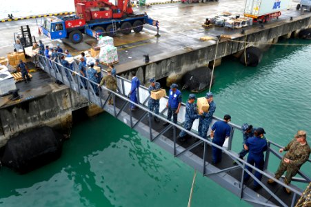 US Navy 111223-N-KS651-081 Sailors, Marines and local nationals bring supplies up the brow of the dock landing ship USS Pearl Harbor (LSD 52)