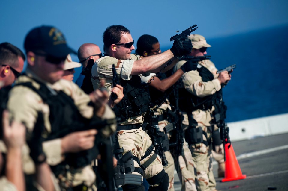US Navy 111231-N-PB383-595 Hull Technician 1st Class James Reams, assigned to the visit, board, search, and seizure team, fires a 9mm pistol at a t