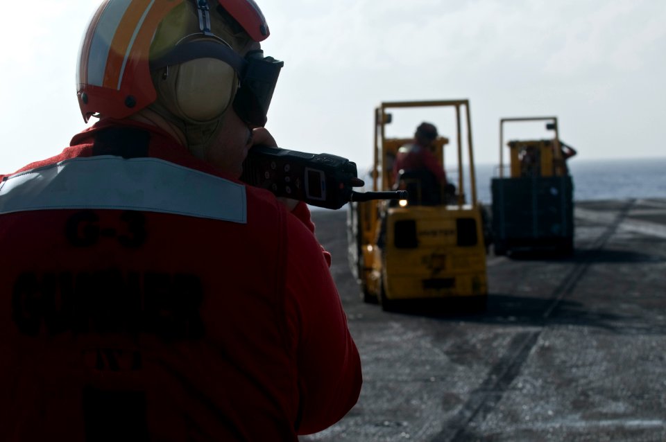 US Navy 111222-N-RG587-204 Lt. James Fish supervises Sailors as they move pallets of ordnance on the flight deck of the Nimitz-class aircraft carri
