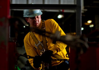 US Navy 111228-N-BT887-069 Aviation Boatswain's Mate (Handling) 2nd Class Ronald Lewis, from Sealy, Texas, tightens support chains for a forklift b