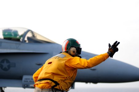 US Navy 111231-N-GZ832-247 Lt. Blake Whetstone, assigned to the air department aboard the aircraft carrier USS Carl Vinson (CVN 70), signals for th