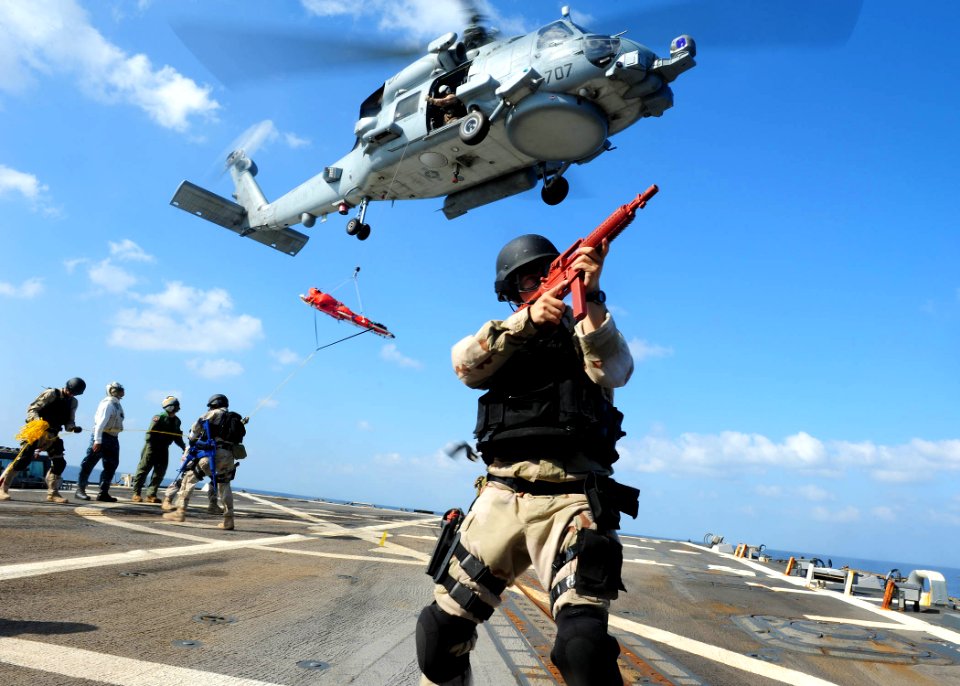 US Navy 111228-N-ED900-562 Ensign Adam Powell keeps watch as other team members prepare a rescue litter for an MH-60R Sea Hawk helicopter assigned