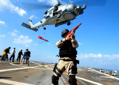 US Navy 111228-N-ED900-562 Ensign Adam Powell keeps watch as other team members prepare a rescue litter for an MH-60R Sea Hawk helicopter assigned