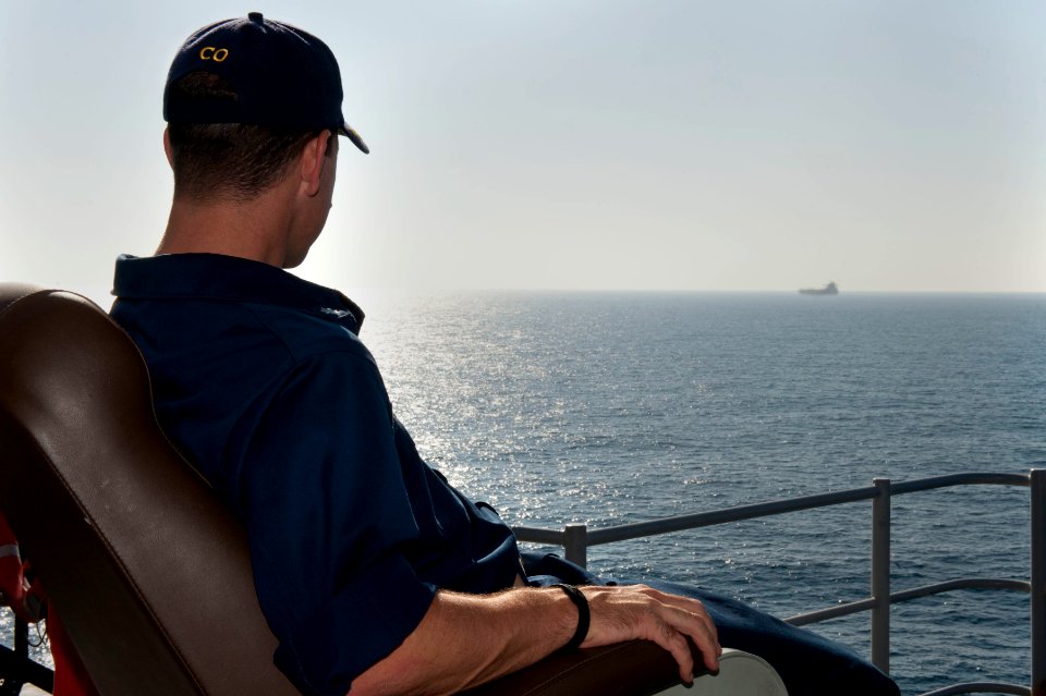 US Navy 111231-N-KS651-202 Cmdr. Homer Denius, commanding officer of the amphibious dock landing ship USS Pearl Harbor (LSD 52), watches a far off