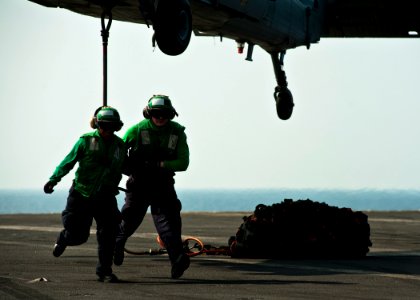 US Navy 111229-N-BT887-517 Logistics Specialist Seamen Tyler Thiebault and Tomiya Norris clear the area after attaching a hook to an MH-60S Sea Haw