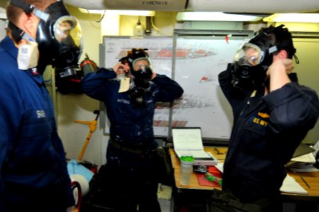 US Navy 111230-N-KS651-302 Sailors aboard the amphibious dock landing ship USS Pearl Harbor (LSD 52) don their gas masks during a general quarters