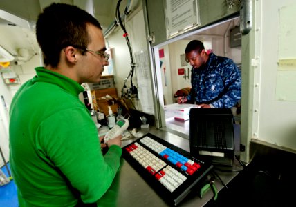 US Navy 111227-N-OY799-209 Logistics Specialist 3rd Class Joel Dunbar, from Boulder City, Nev., assists Aviation Ordnanceman Airman Eric Terrell, f