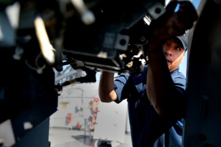 US Navy 111231-N-KS651-444 Gunners Mate 1st Class Johnny Salinas performs maintenance on a Mk 38 MOD 2 25mm machine gun system aboard the amphibiou