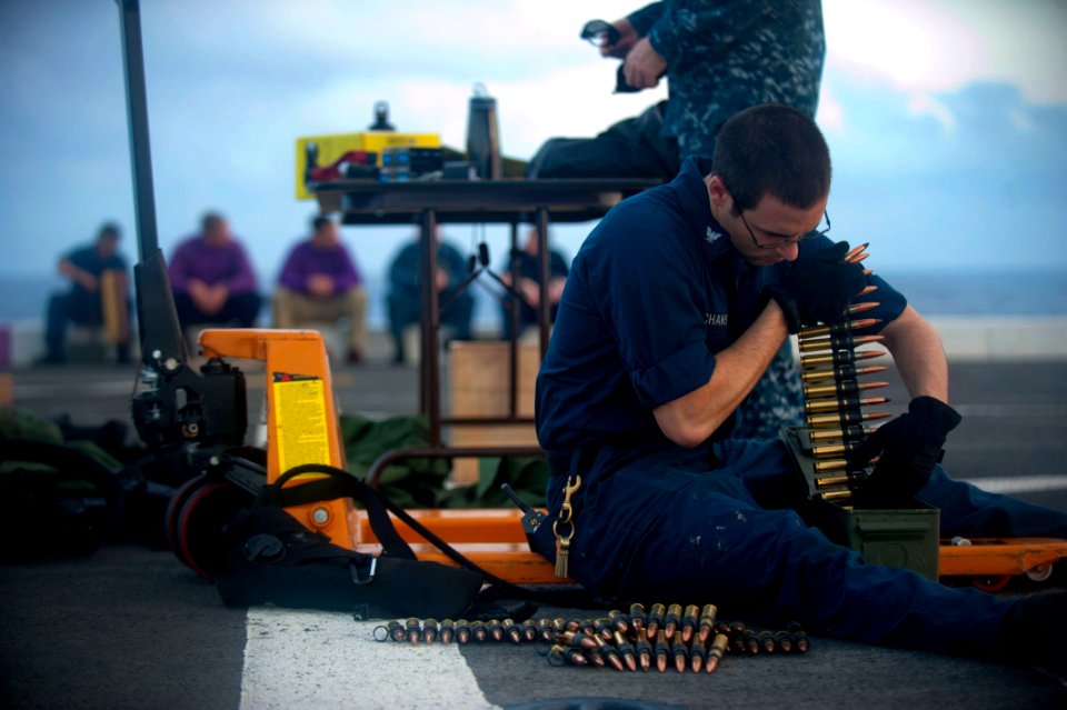 US Navy 111229-N-PB383-138 Gunner's Mate 3rd Class Joshua Velchansky organizes .50-caliber machine gun ammunition during a live-fire exercise aboar