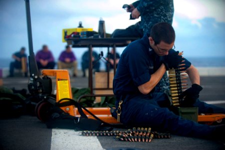 US Navy 111229-N-PB383-138 Gunner's Mate 3rd Class Joshua Velchansky organizes .50-caliber machine gun ammunition during a live-fire exercise aboar