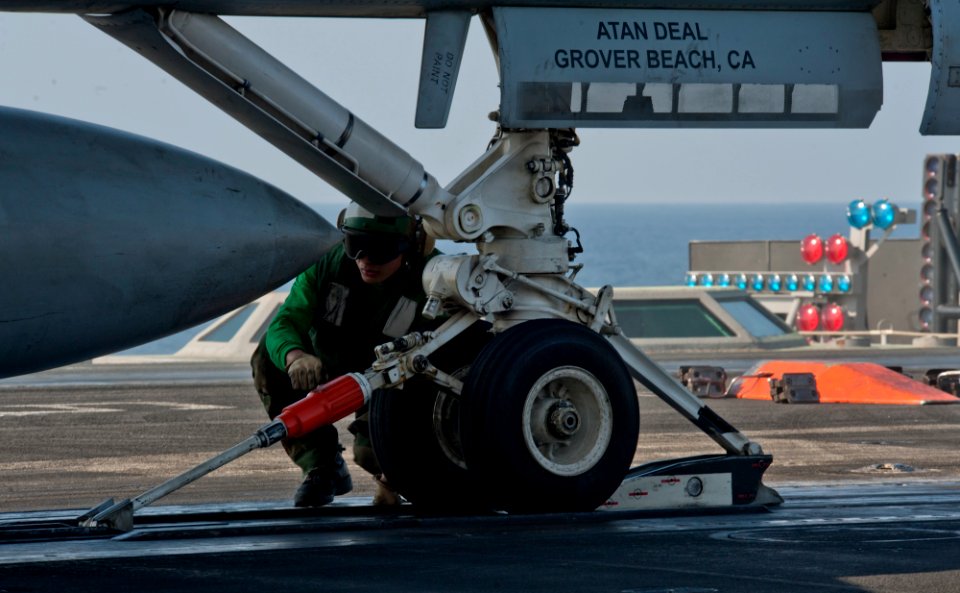 US Navy 111229-N-OY799-138 Aviation Boatswain's Mate (Equipment) 3rd Class Alfred Ranili checks the hold back bar prior to launching an aircraft on