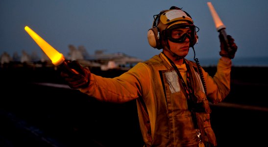 US Navy 120103-N-OY799-272 Aviation Boatswain's Mate (Handling) 3rd Class Eric Augustine directs a fixed wing aircraft onto catapult three