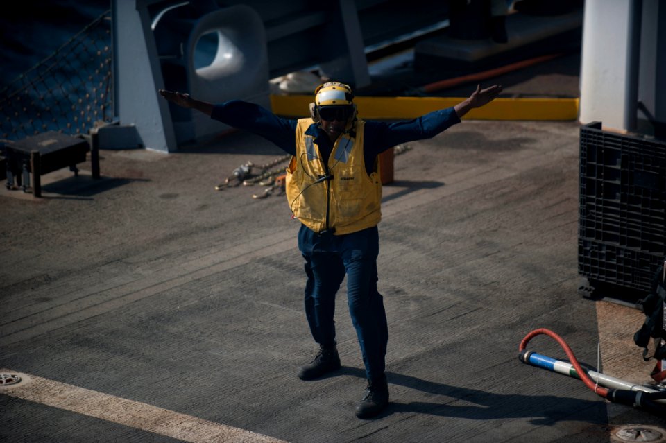 US Navy 120104-N-PB383-864 A civilian landing signalman lands a helicopter during a replenishment at sea