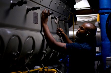 US Navy 120110-N-TZ605-202 ngineman 3rd Class Mark Jones performs maintenance on an engine valve in an emergency diesel generator space