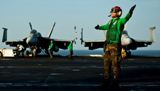 US Navy 120105-N-BT887-323 Aviation Machinist's Mate 3rd Class Ian Drake signals to an MH-60S Knight Hawk helicopter from the Eightballers of Helic
