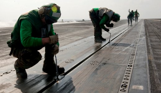 US Navy 120108-N-OY799-117 Sailors replace catapult buttons on the flight deck of the Nimitz-class aircraft carrier USS John C. Stennis (CVN 74)