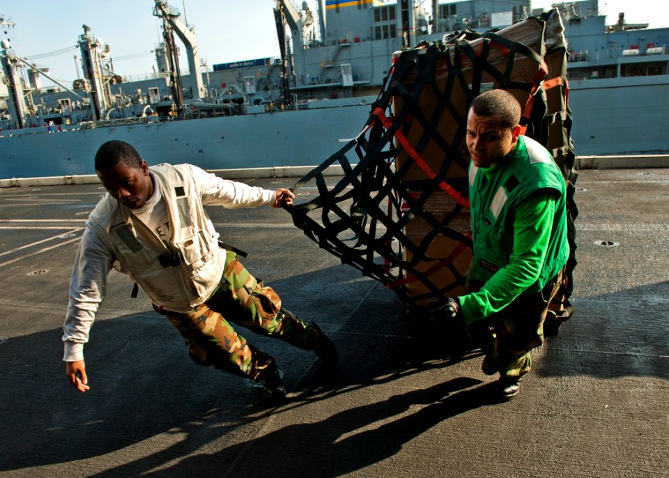 US Navy 120105-N-BT887-589 Yeoman 3rd Class Jaren Cleveland and Logistics Specialist Seaman Luis Colon pull cargo aboard the Nimitz-class aircraft