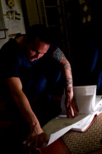 US Navy 120105-N-TZ605-211 Electrician's Mate 3rd Class Joshua Scammell eviews electrical schematics while troubleshooting an air conditioning powe