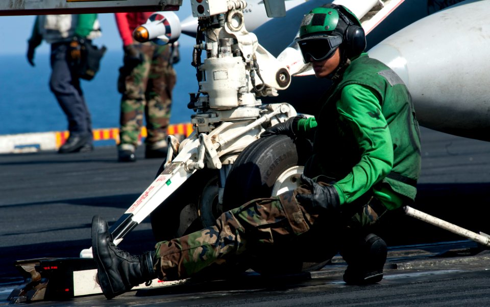 US Navy 120104-N-OY799-114 Aviation Boatswain's Mate (Equipment) 3rd Class Carlaldrin Milana signals for a fixed wing aircraft to move forward on t